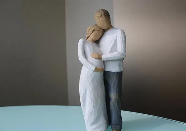 A carved figurine of an expecting couple embracing